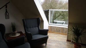 A room with a sloped ceiling, a large window, and a chair.