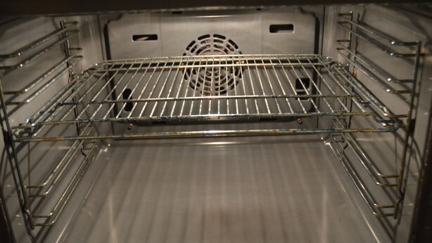 An empty oven with a metal rack and a vent in the center.
