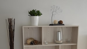 En bokhylla i trä med flera hyllplan, varav några innehåller dekorativa föremål och en växt.