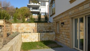 En innergård med stenmurar, en stenlagd gångväg och en byggnad med en glasdörr och en lykta.