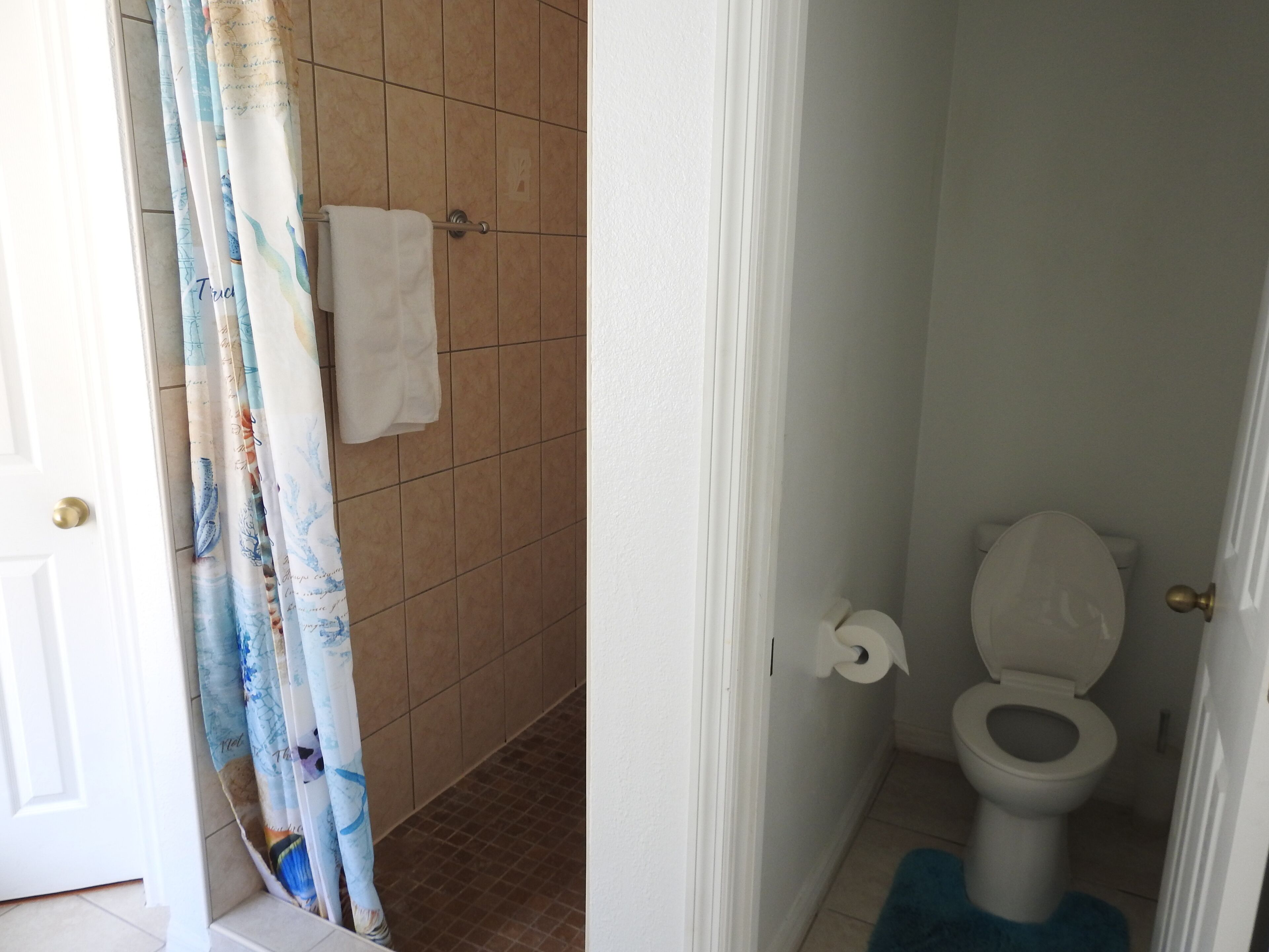 Een badkamer met douche, toilet en een handdoekhouder.