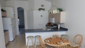 Uma cozinha moderna com uma ilha central, cadeiras de madeira e uma mesa de jantar.