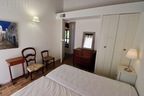 Un dormitorio con cama, cómoda, silla, escritorio y un cuadro en la pared.
