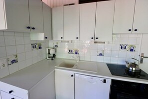 Una cocina con gabinetes blancos, lavavajillas y estufa.