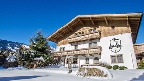 A traditional alpine hotel with a wooden facade, balconies, and a mountain backdrop.