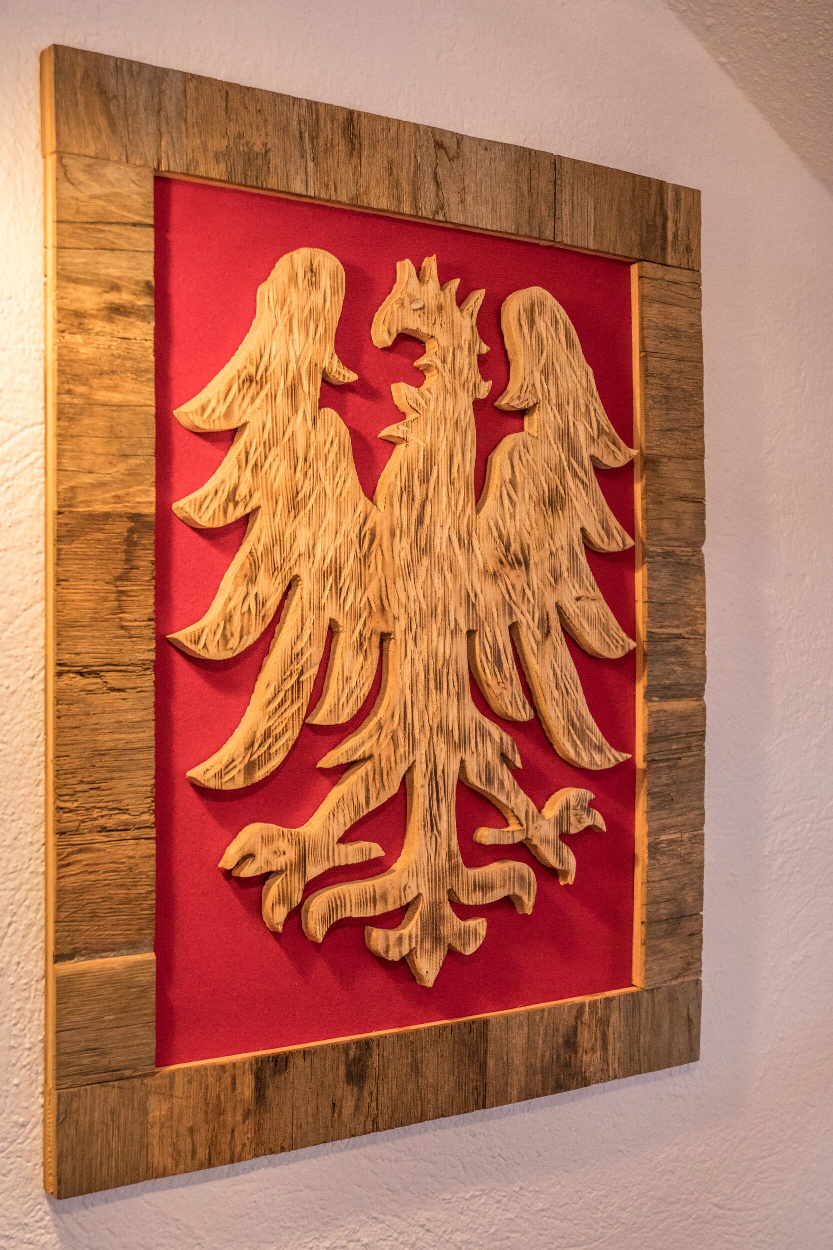 A wooden relief of a double-headed eagle on a red background, framed in wood.