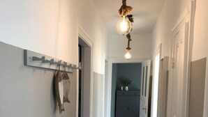 A hallway with wooden flooring, white walls, and a ceiling light fixture.