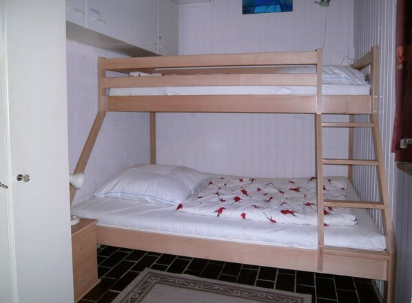 A bunk bed with white bedding and red rose petals scattered on the lower bed.
