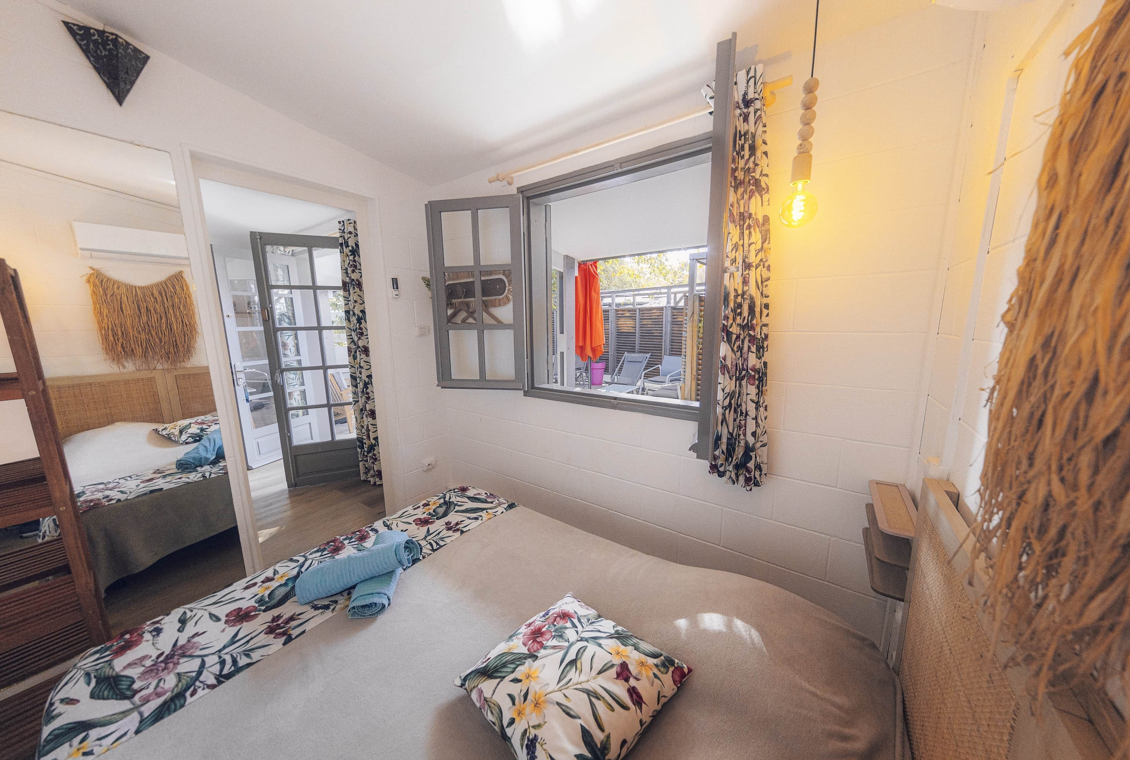 Une chambre avec un lit, une fenêtre donnant sur un beau paysage, un miroir et un luminaire suspendu.