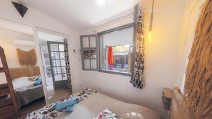 A room with a bed, a window with a view, a mirror, and a hanging light fixture. - BUNGALOW T3 PITAYA (Saint-Paul)