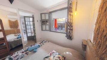 Une chambre avec un lit, une fenêtre donnant sur un beau paysage, un miroir et un luminaire suspendu.