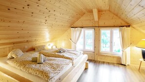 Un dormitorio de cabaña de madera con dos camas, una ventana y una lámpara.