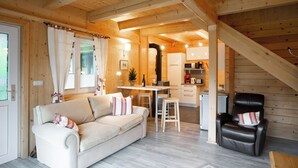 Un interior de cabaña acogedor con un sofá, un comedor y una cocina.