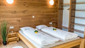 Une pièce en bois avec deux lits, une armoire en bois et une plante en pot.