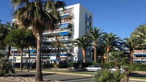 Un hôtel à plusieurs étages doté de balcons, de palmiers et d’une piste cyclable.