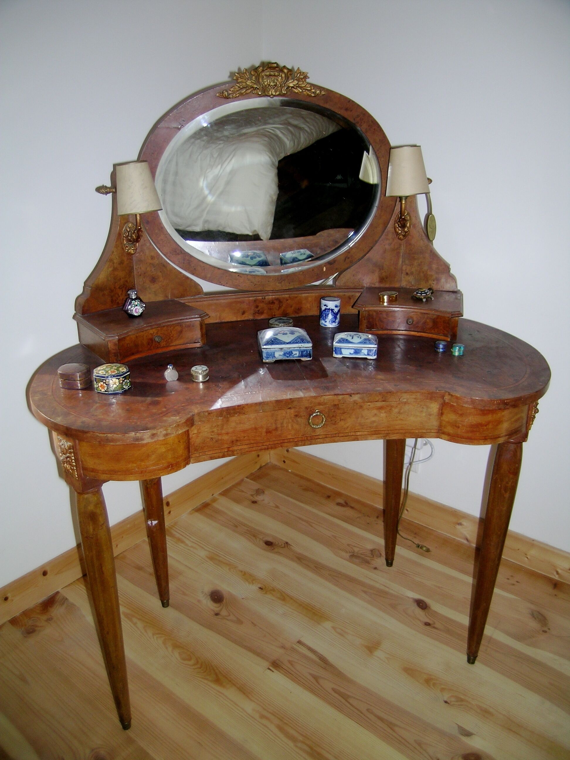 A wooden vanity with a mirror, two lamps, and several small containers.