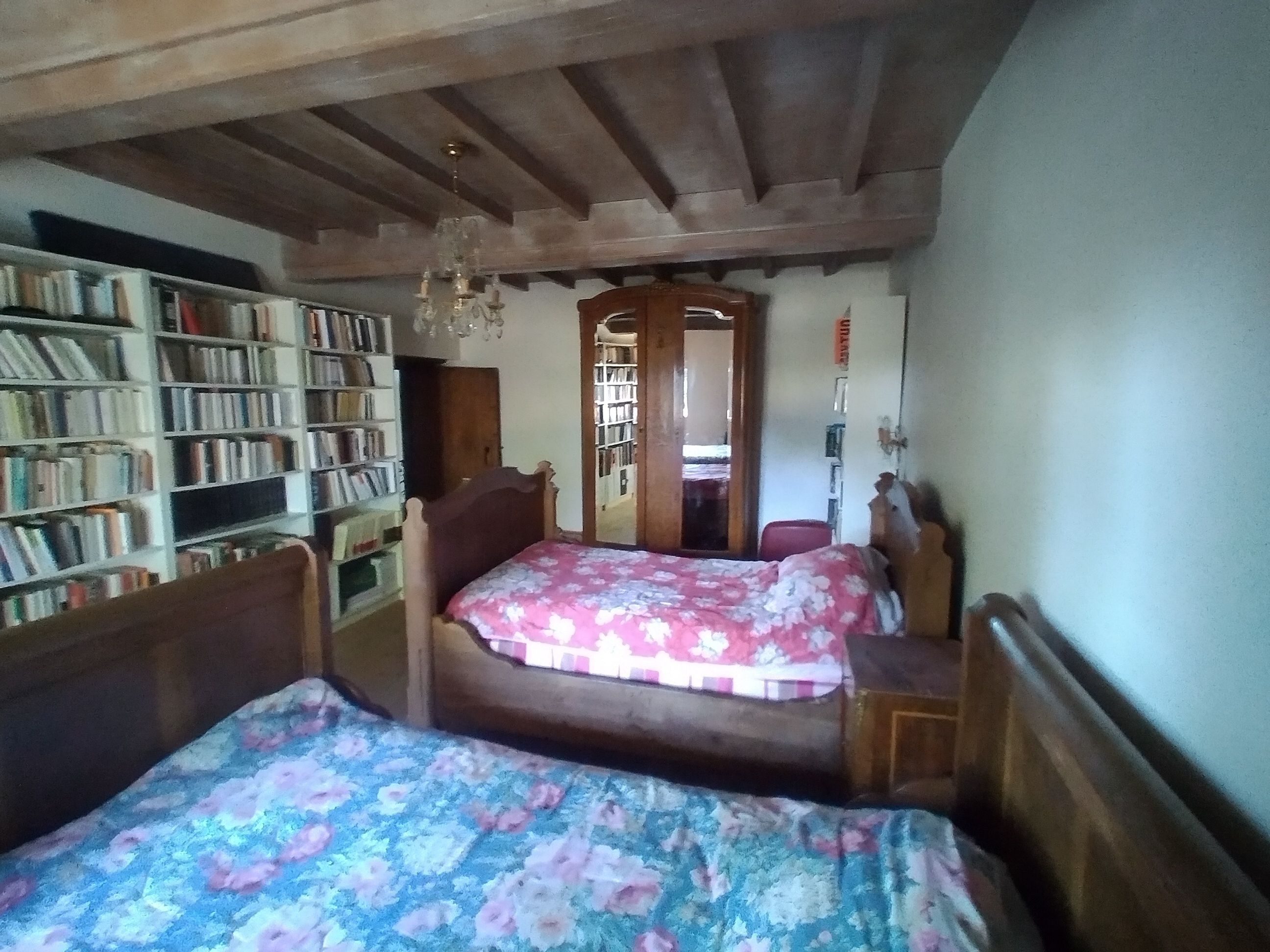 Ein Schlafzimmer mit zwei Holzbetten, einem Bücherregal und einer Kronleuchter.