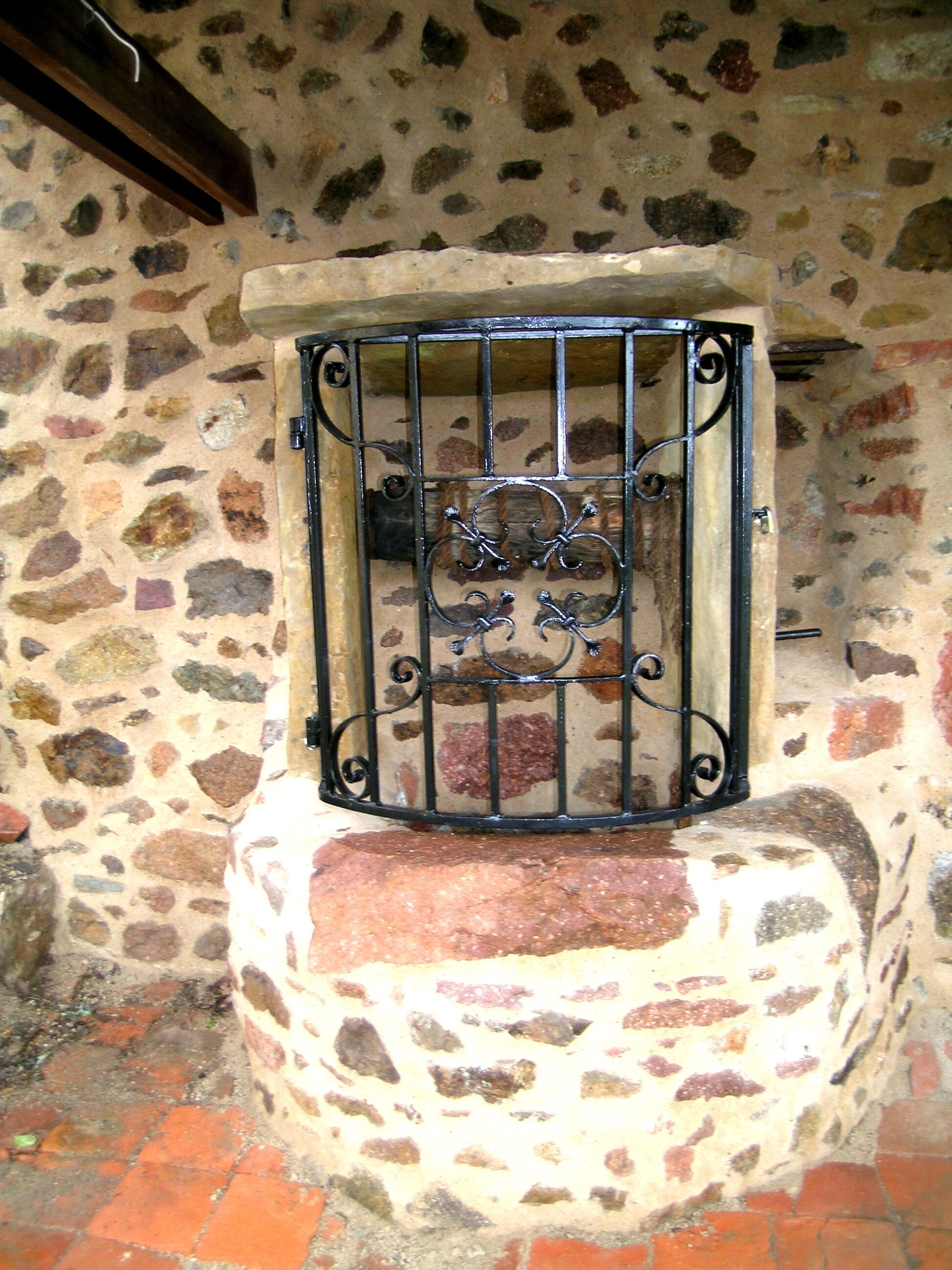 Een stenen muur met een metalen hek en een decoratief embleem.