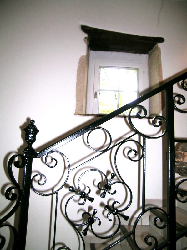 A staircase with ornate black metal railings and a small window at the top.
