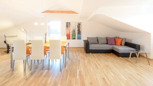 A modern loft apartment with a dining area, a sofa, and a glass coffee table.