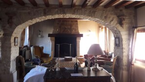 Un salon chaleureux avec une cheminée en pierre, des poutres en bois et une arche en pierre.