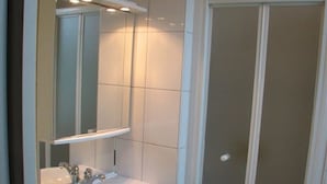 Een badkamer met een wit wastafelmeubel, spiegel en douchecabine.