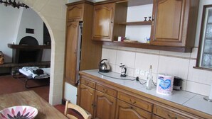 Een keuken met houten kastjes, een aanrecht, een waterkoker en een fles melk.