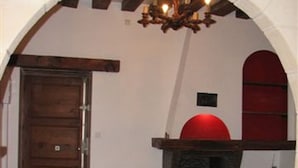 Een kamer met een stenen open haard, een houten deur en een gewelfd plafond.