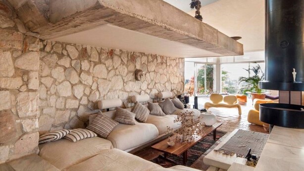 A spacious living area with a stone wall, a large sofa set, a coffee table, and a fireplace.