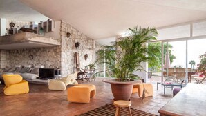 A spacious living area with a stone wall, a large potted plant, and a modern sofa set.