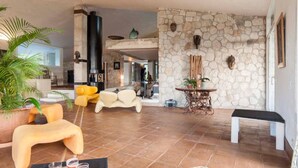 A spacious living area with a stone wall, modern furniture, and a fireplace.