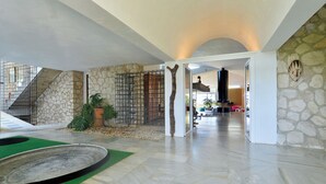 A spacious interior with a stone wall, a staircase, and a large mirror reflecting a room with a fireplace.