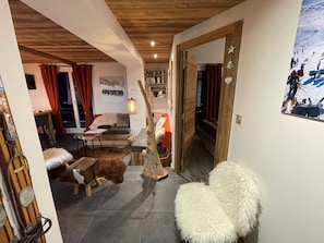 A cozy living room with a wooden ceiling, a sofa, a dog, a fluffy chair, and a painting of a snowy mountain scene. - Appart ski aux pieds 8 pers : 3ch 2sdb - Sheets-Linen-Household-Wifi-Parking-TV's (Les Deux alpes - Mont de Lans)