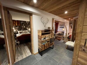 A modern interior with a wooden ceiling, a bed with a patterned headboard, a wooden chest of drawers, and a cozy seating area with a rug and a small table. - Appart ski aux pieds 8 pers : 3ch 2sdb - Sheets-Linen-Household-Wifi-Parking-TV's (Les Deux alpes - Mont de Lans)