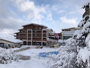 A multi-story hotel with a ski resort in the background. - Appart ski aux pieds 8 pers : 3ch 2sdb - Sheets-Linen-Household-Wifi-Parking-TV's (Les Deux alpes - Mont de Lans)