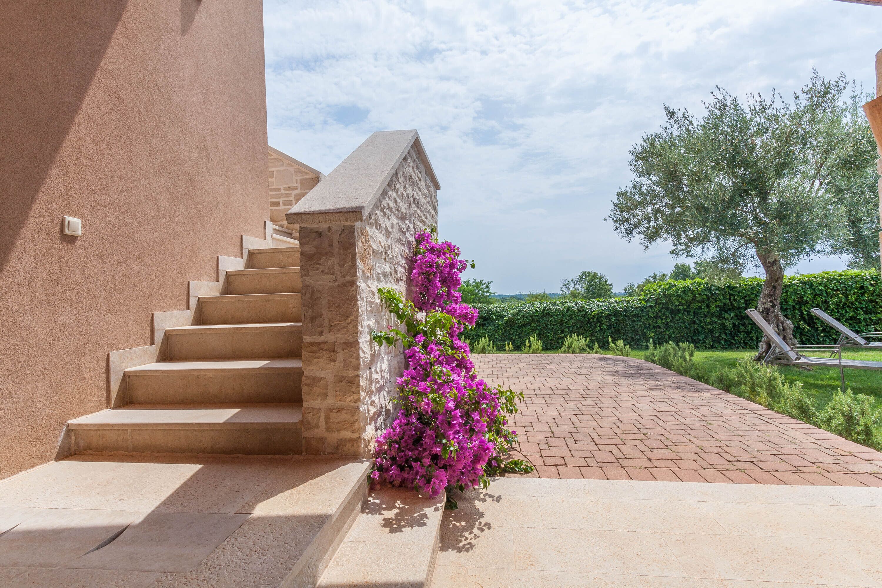 A stone staircase leading to a building with a pink flowering bush beside it.