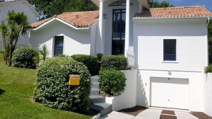 A two-story house with a white exterior, a tiled roof, and a front entrance with a covered porch. - BRIGHT VILLA WITH POOL (Moliets-et-Maa)