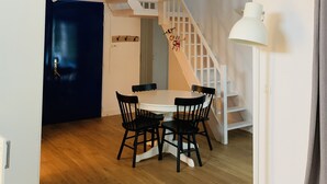 A room with a wooden floor, a white table with four chairs, a blue door, a staircase with a white railing, and a white lamp. - BRIGHT VILLA WITH POOL (Moliets-et-Maa)