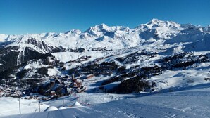 A snow-covered mountain landscape with ski slopes and a small town nestled in the valley.