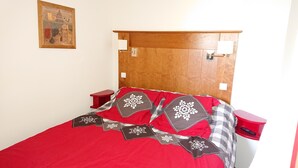 A bed with a red and gray checkered bedspread, wooden headboard, and two bedside tables with lamps.
