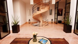 Stunning interior space with a central spiral staircase, flanked by lantern-style lights and a framed picture, set against a light-colored backdrop.