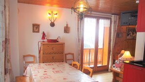 A cozy dining area with a table set for two, a wooden cabinet with drawers, a chandelier, and a television mounted on the wall. - T2 / 36M² FOR 5 PEOPLE 100M FROM THE MECHANICAL RIDGE IN THE HEART OF PARADISKI (Peisey-Nancroix)