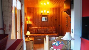A cozy room with wooden walls, a sofa, a table with a lamp, and a wall-mounted TV. - T2 / 36M² FOR 5 PEOPLE 100M FROM THE MECHANICAL RIDGE IN THE HEART OF PARADISKI (Peisey-Nancroix)
