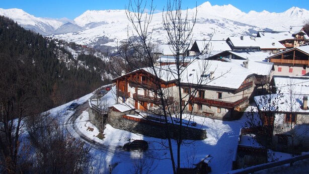 A snow-covered mountain village with traditional wooden buildings, a winding road, and a clear blue sky. - T2 / 36M² FOR 5 PEOPLE 100M FROM THE MECHANICAL RIDGE IN THE HEART OF PARADISKI (Peisey-Nancroix)