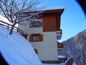 A multi-story building with wooden balconies and a snow-covered landscape.