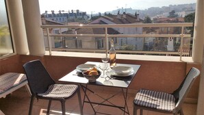A balcony with a table set for two, chairs, and a view of the cityscape. - Melo's Studio with amazing views of Cannes and the sea as well as WiFi (Cannes)