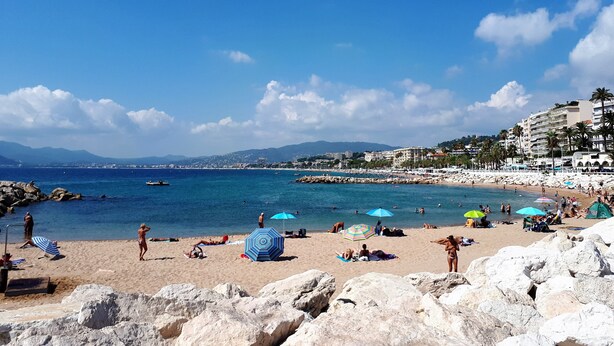 A beach with rocky foreground, clear blue water, and buildings in the background. - Melo's Studio with amazing views of Cannes and the sea as well as WiFi (Cannes)
