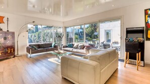 A spacious living room with large windows, a sofa, a coffee table, and a cabinet.