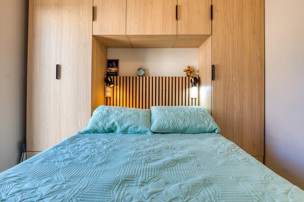 Un dormitorio con cama, armario de madera y un reloj en la pared.