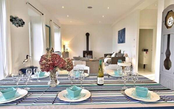 A dining area with a striped tablecloth, a central floral arrangement, and a bottle of wine. - House "La Terrasse de Sophie" sea view in Plougasnou in Finistère (Plougasnou)